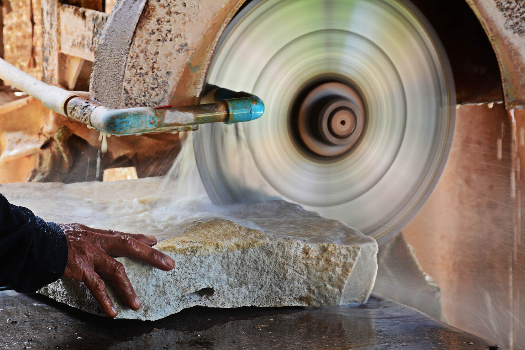 Close,up,hand,of,stone,mason,cutting,sandstone,by,industrial