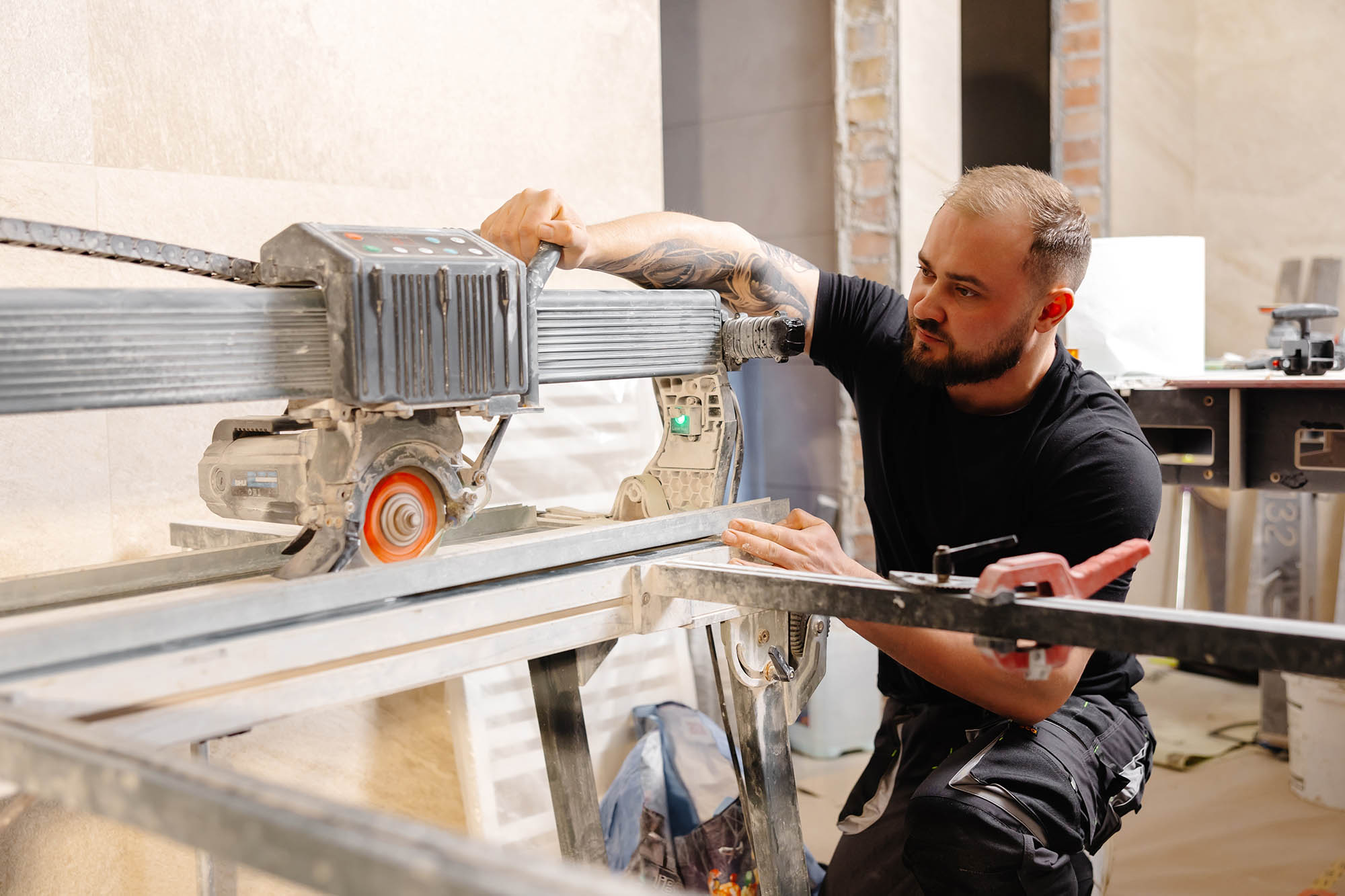 Builder,cutting,ceramic,tile,with,a,wet,saw,machine,at